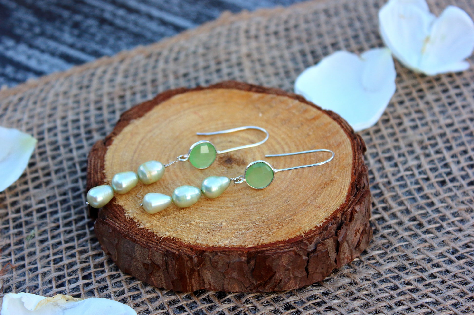 Pair of earrings with green stones on a wooden surface.