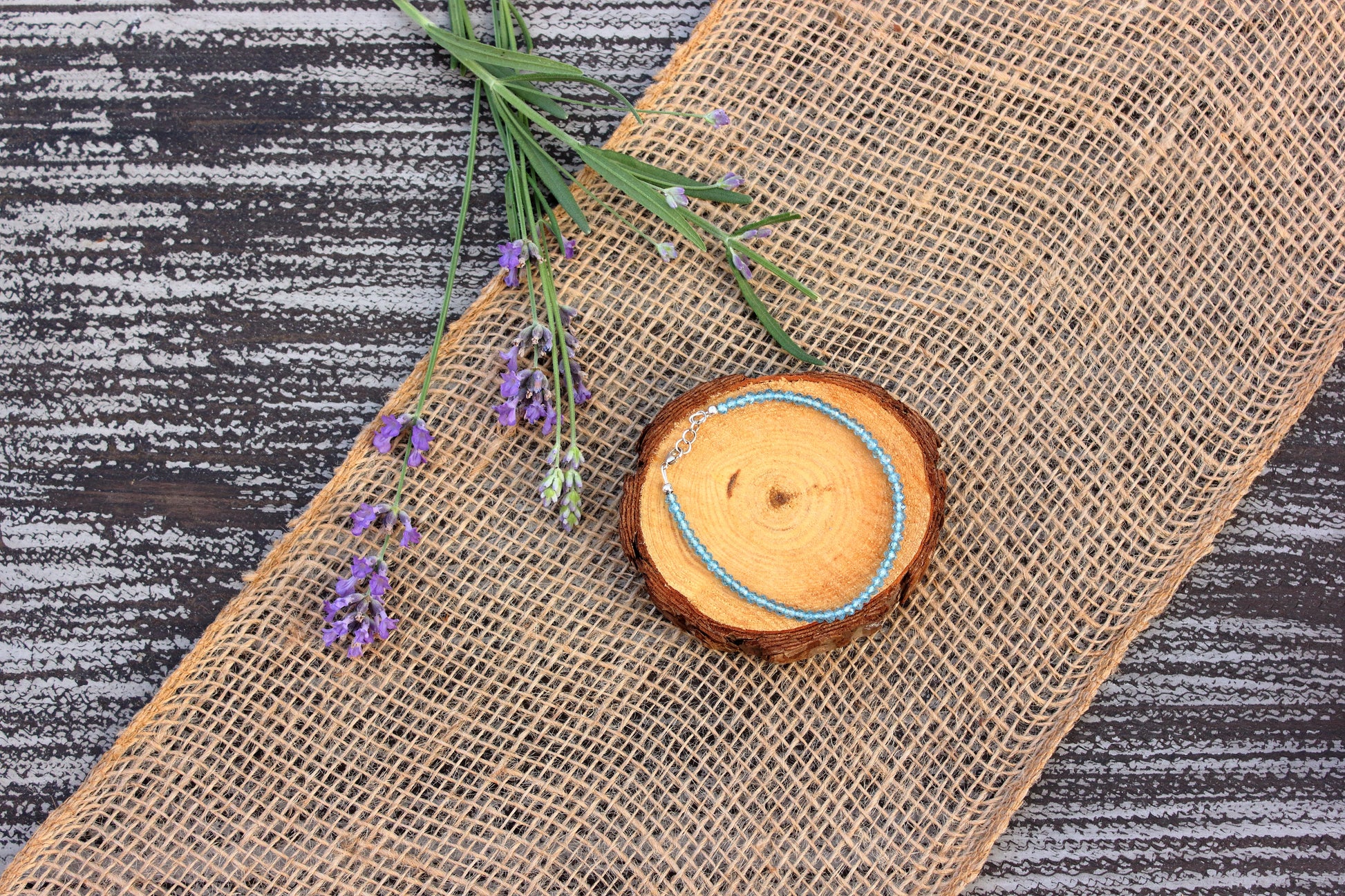 Wooden slice with a blue string on a textured surface with lavender flowers