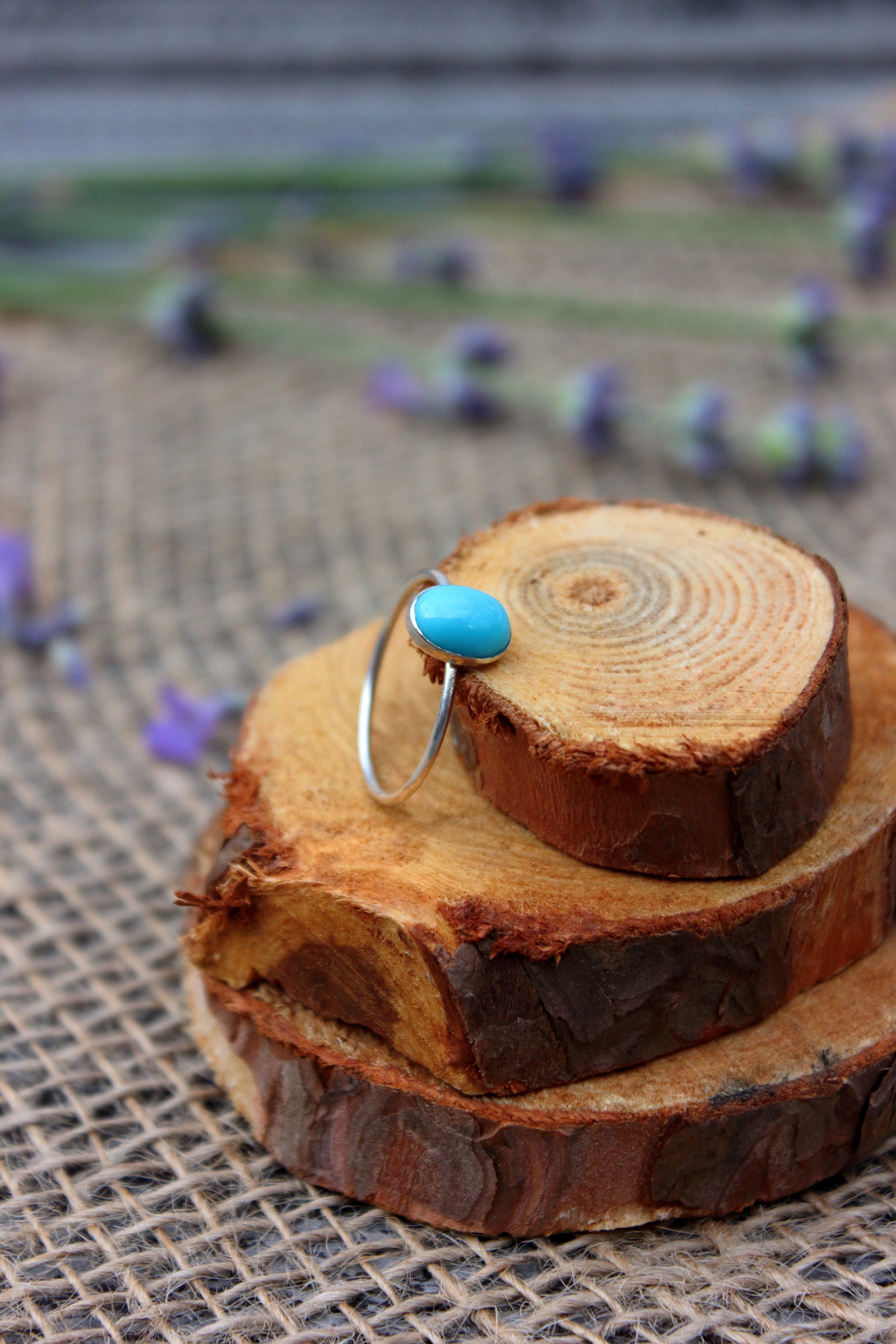 Turquoise ring on a stack of wooden slices with a blurred outdoor background