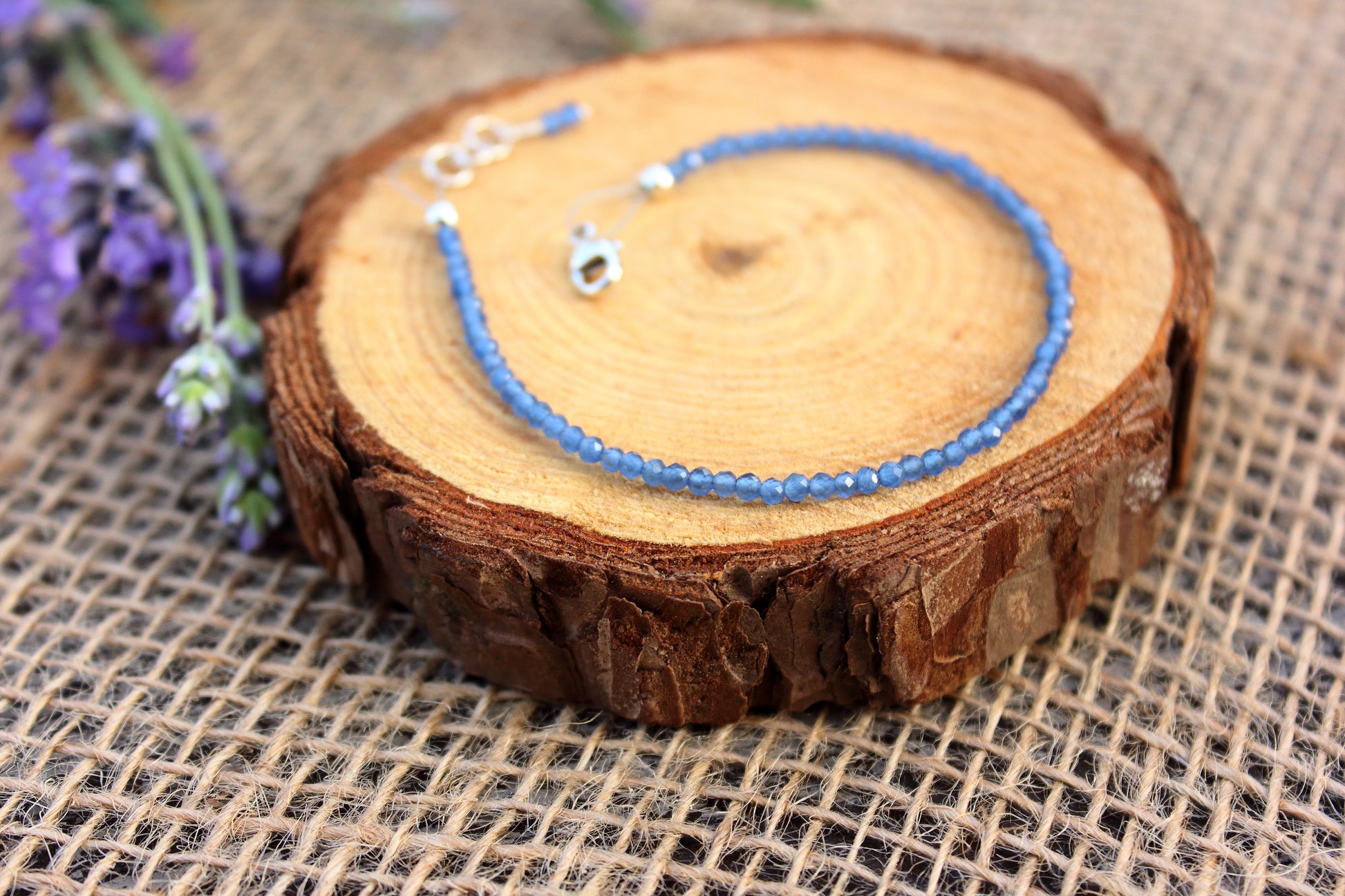 Blue beaded bracelet on a wooden slice with lavender flowers
