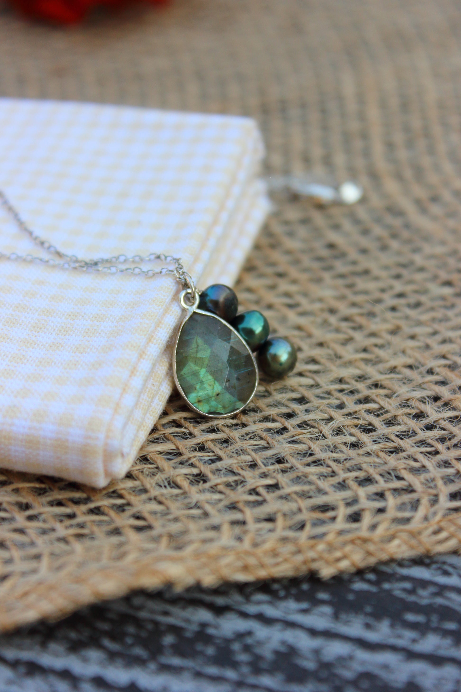 Necklace with green pendant on a beige fabric background