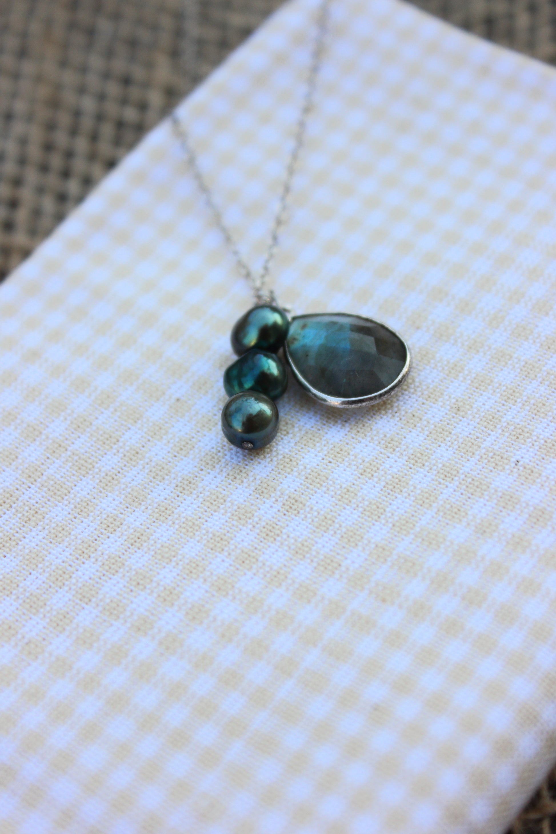 Necklace with green gemstones on a checkered fabric background