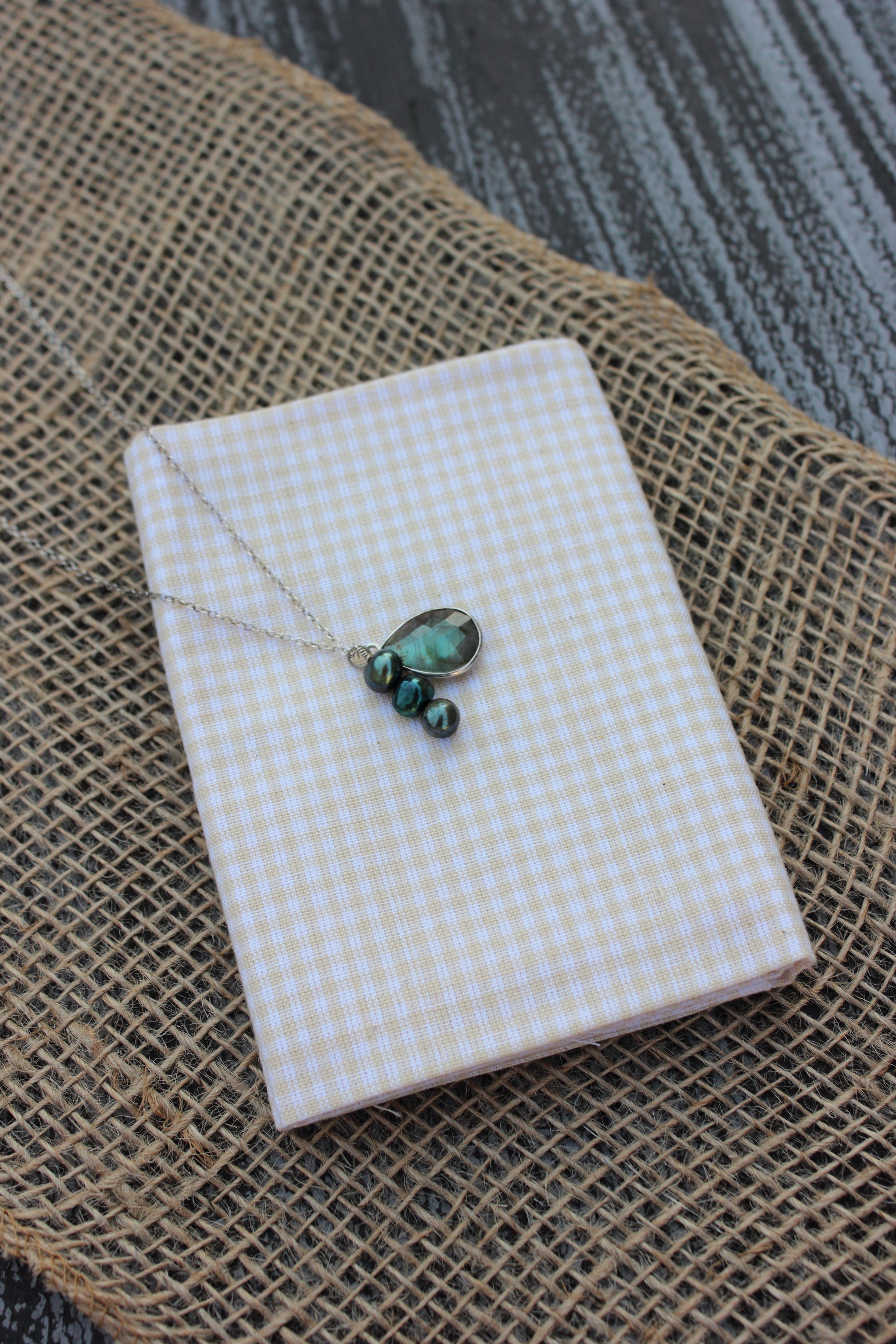 Necklace with green beads on a white checkered box on a textured surface