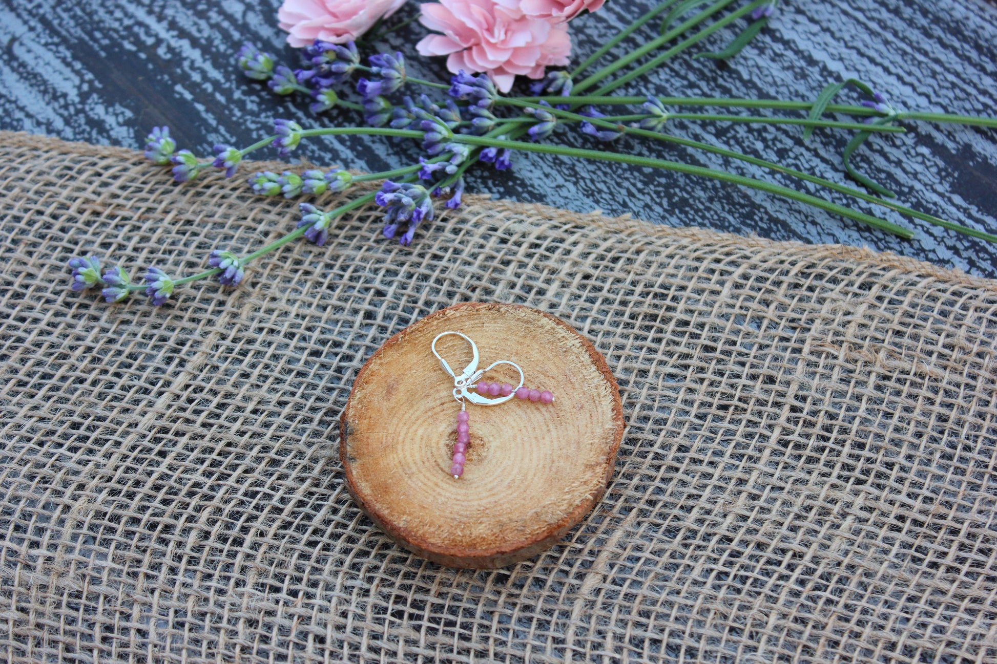 Jewelry on a wooden slice with flowers in the background