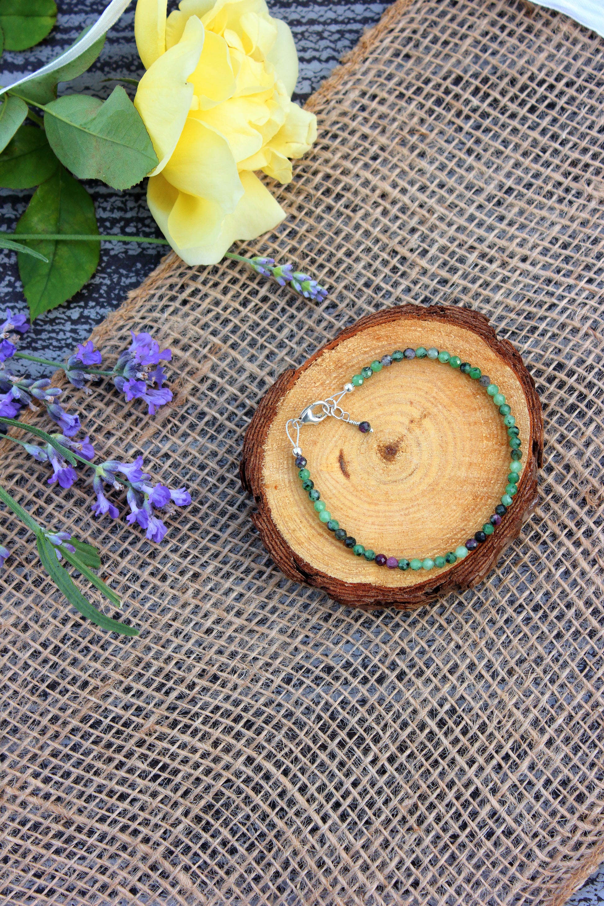 Bracelet on a wooden slice with flowers in the background