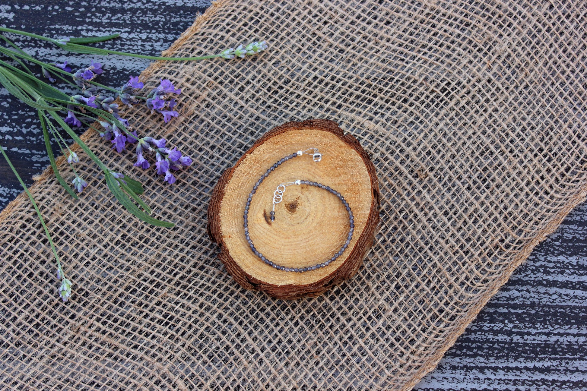 Bracelet with spiral design on a textured fabric background with lavender flowers.