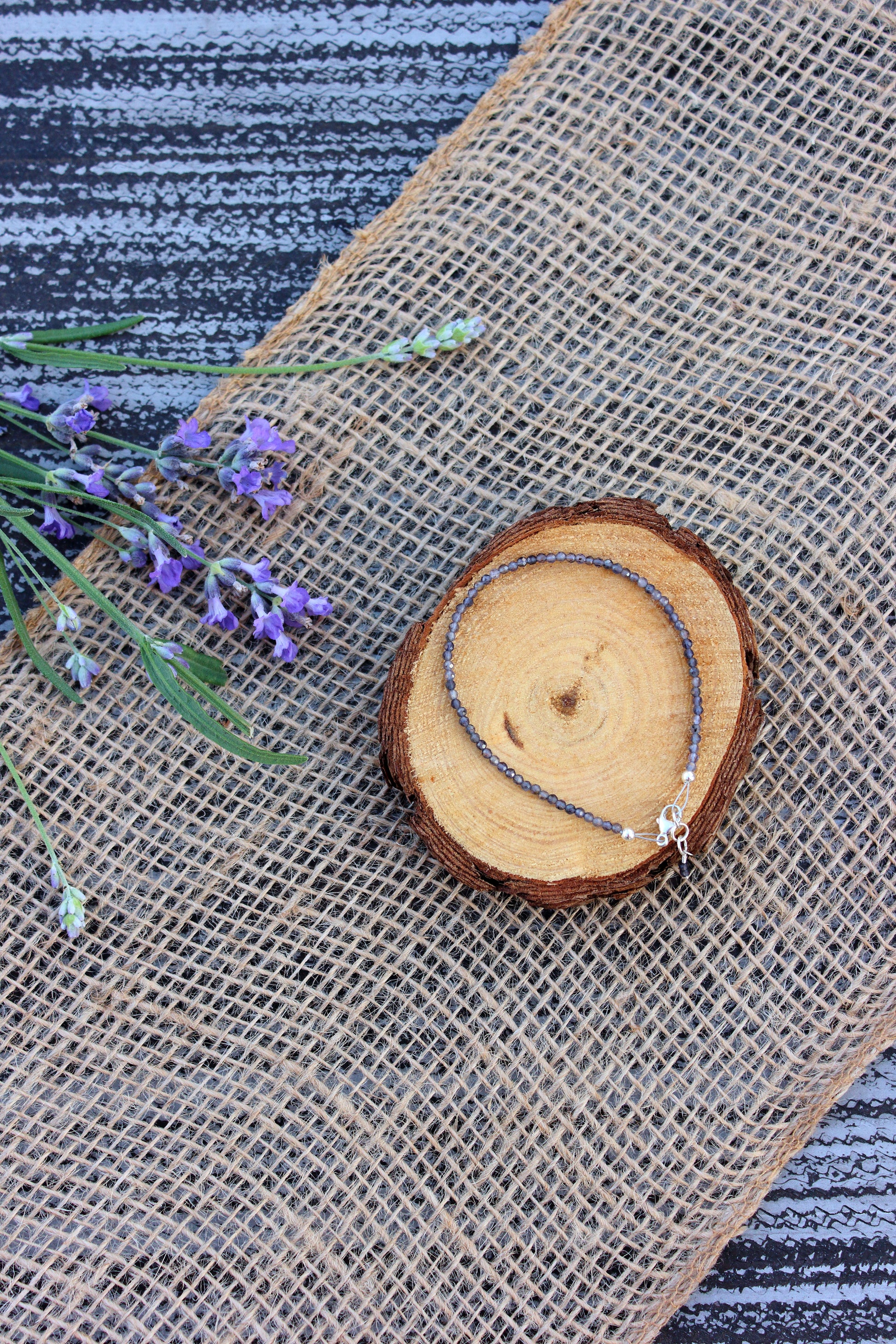 Bracelet on a wooden slice with lavender flowers on a textured fabric background
