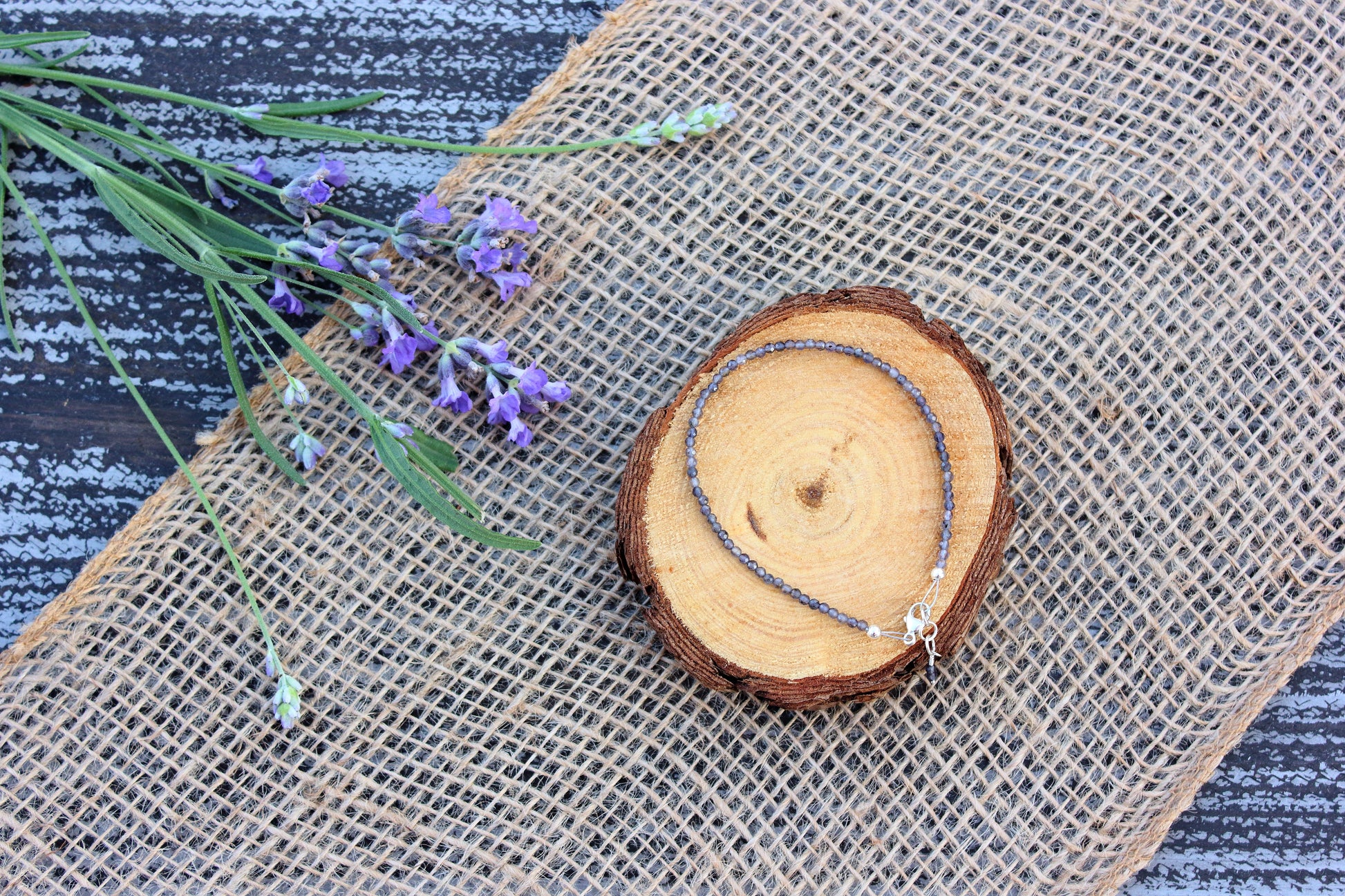 Wooden slice with a purple bracelet on a textured fabric background