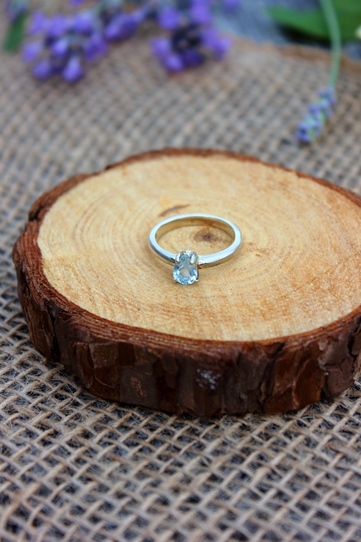 Silver ring with a clear gemstone on a wooden surface