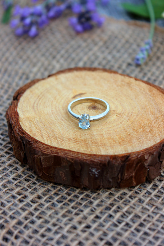 Silver ring with a clear gemstone on a wooden surface