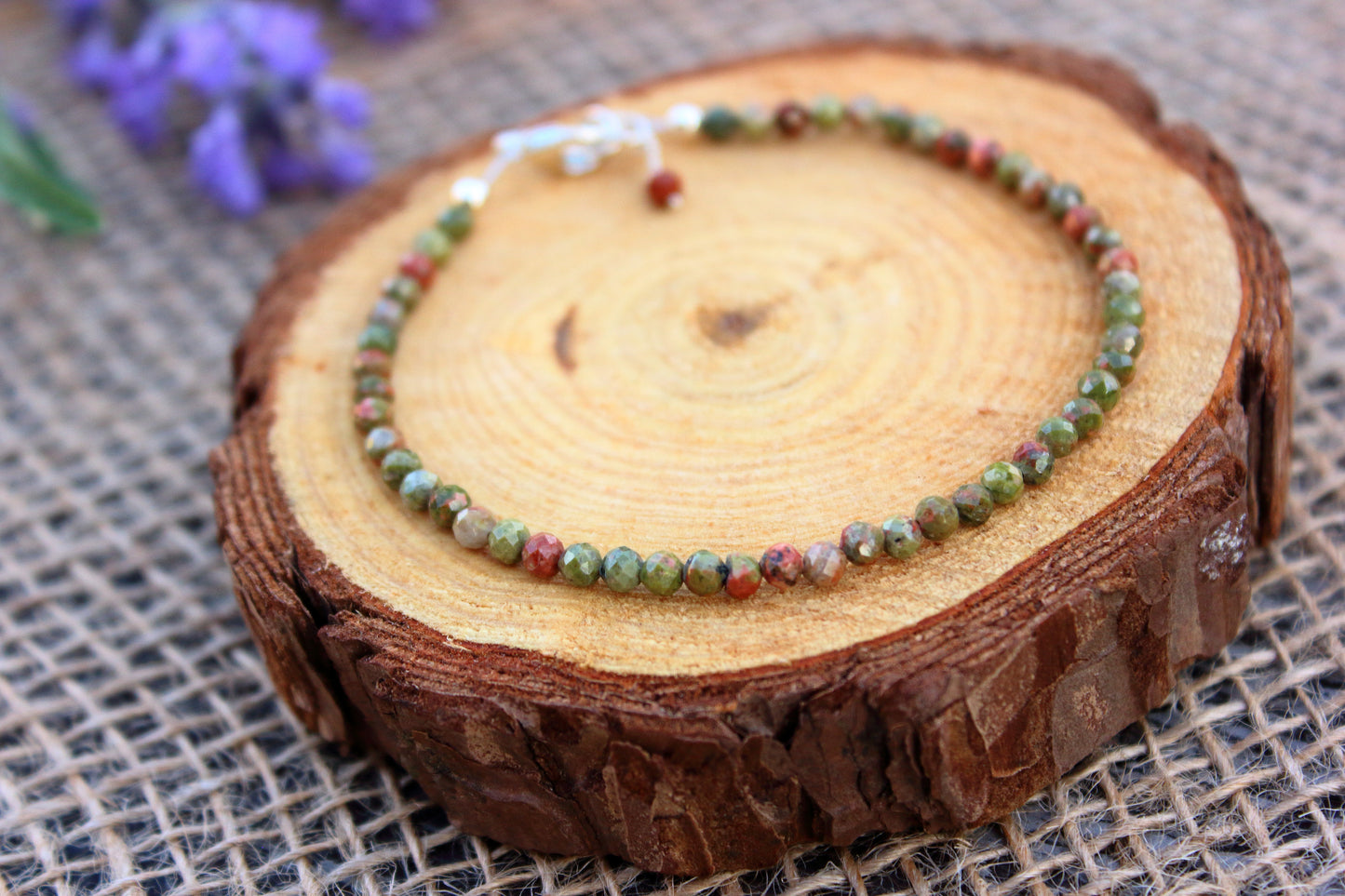 Beaded bracelet on a wooden slice with a blurred floral background