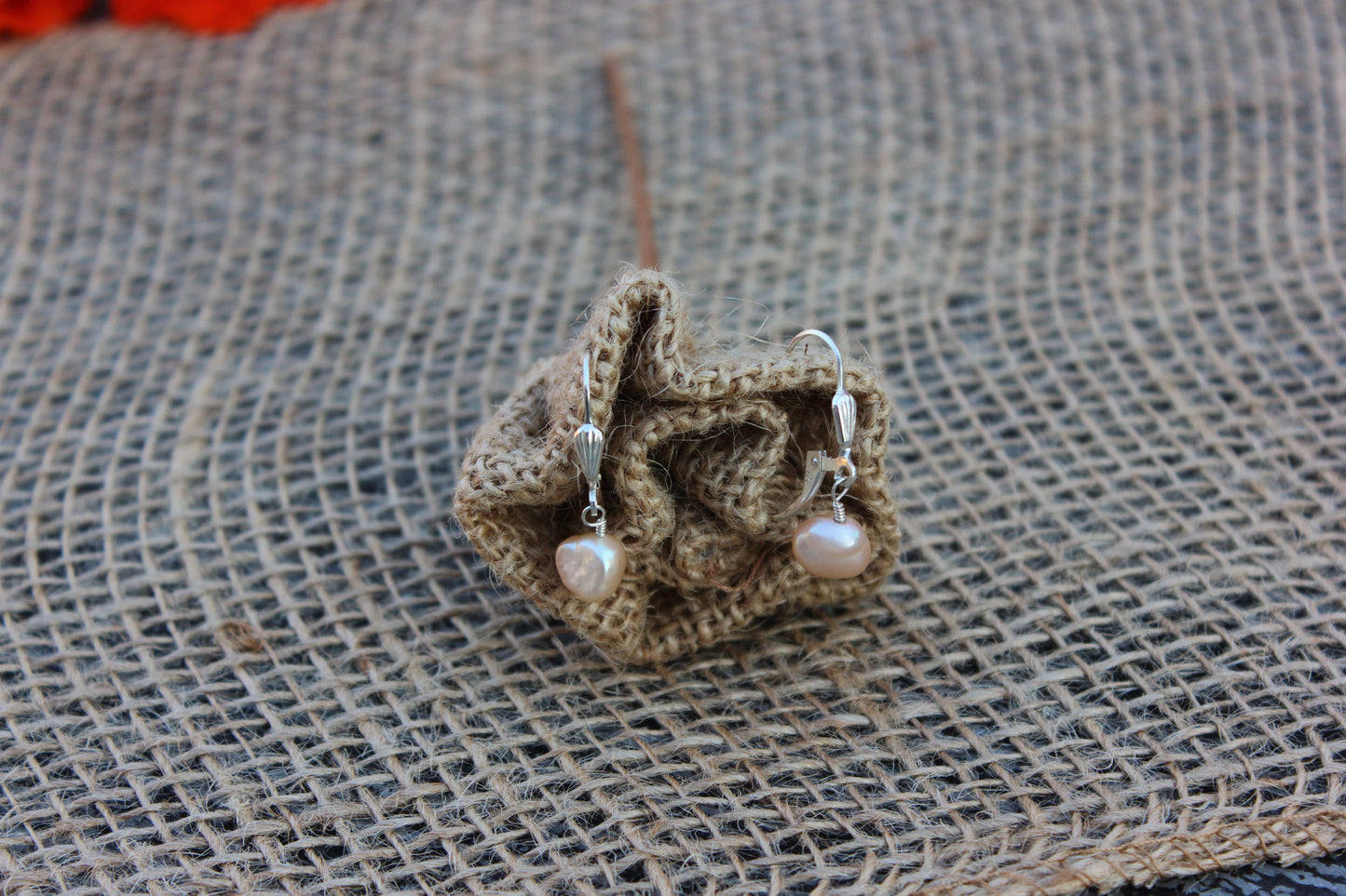 Pearl earrings on a textured fabric surface