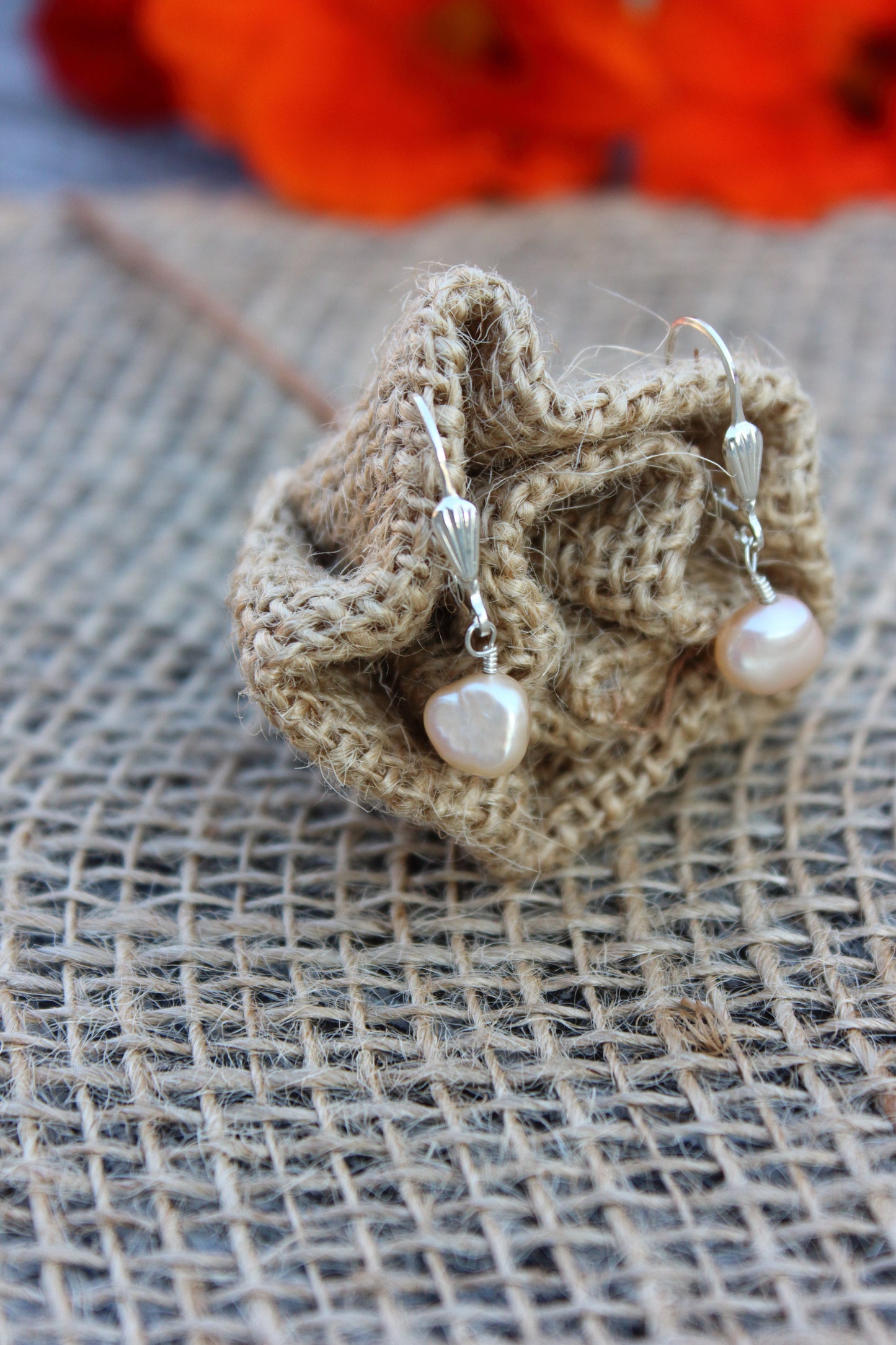 Burlap flower with pearl earrings on a textured surface