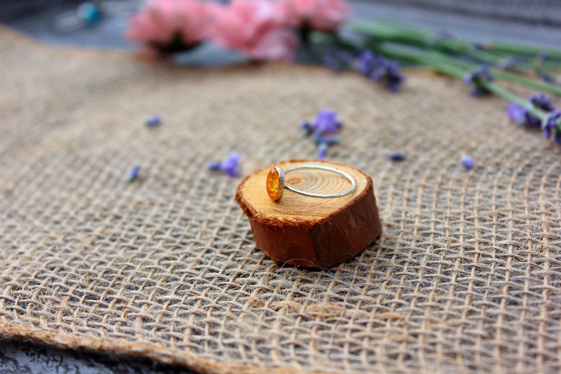Ring on a wooden block with flowers in the background
