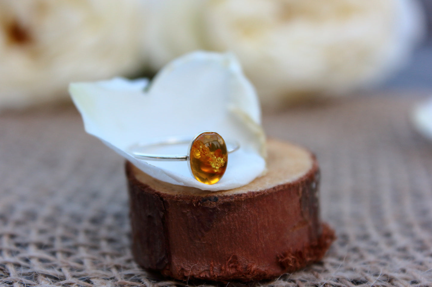 Ring with a amber stone on a wooden block with a white cloth