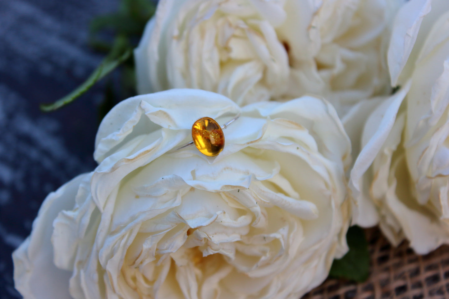 Close-up of a white rose with a yellow gemstone on a textured surface