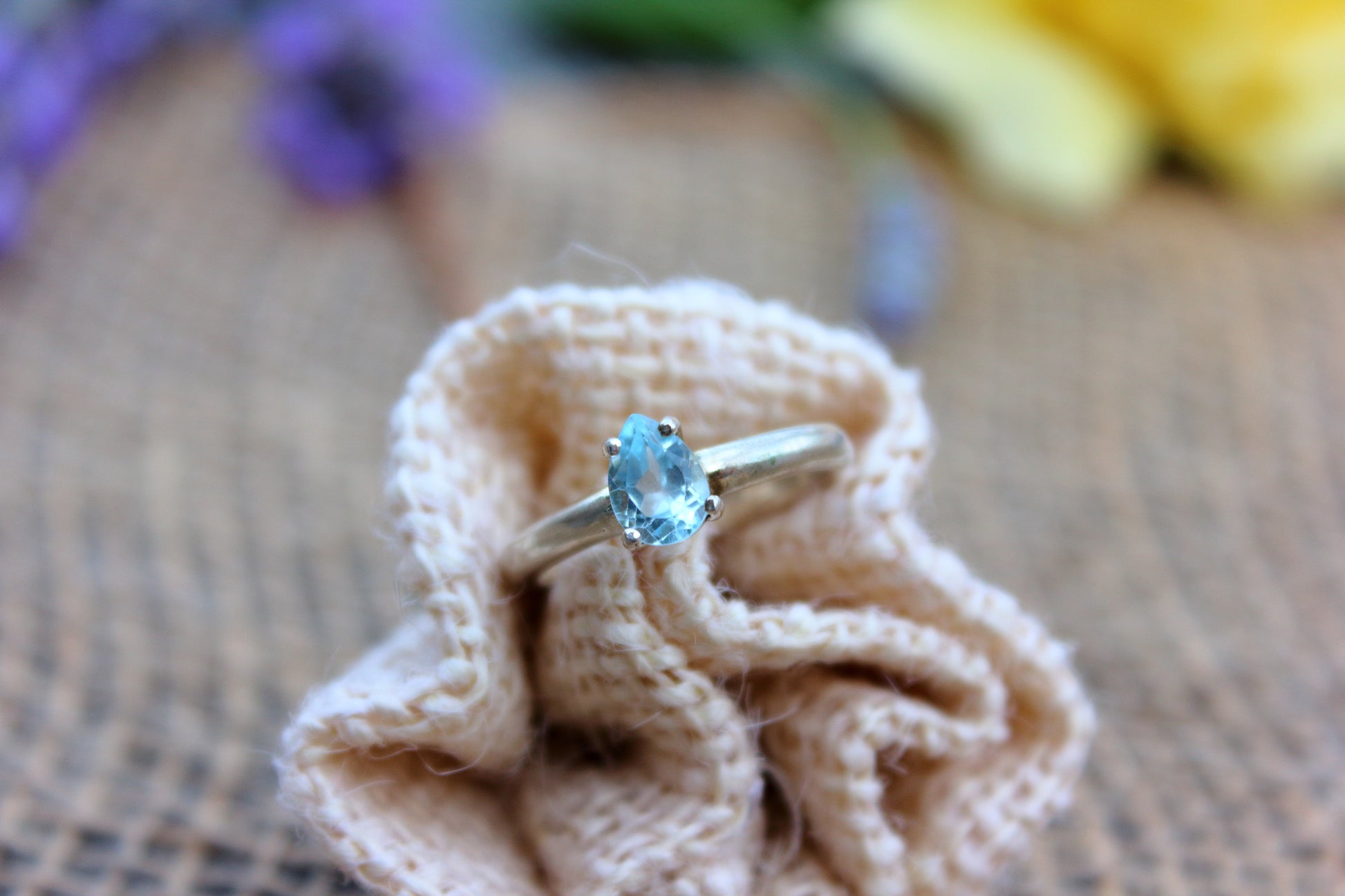 Gold ring with a blue gemstone on a textured fabric surface
