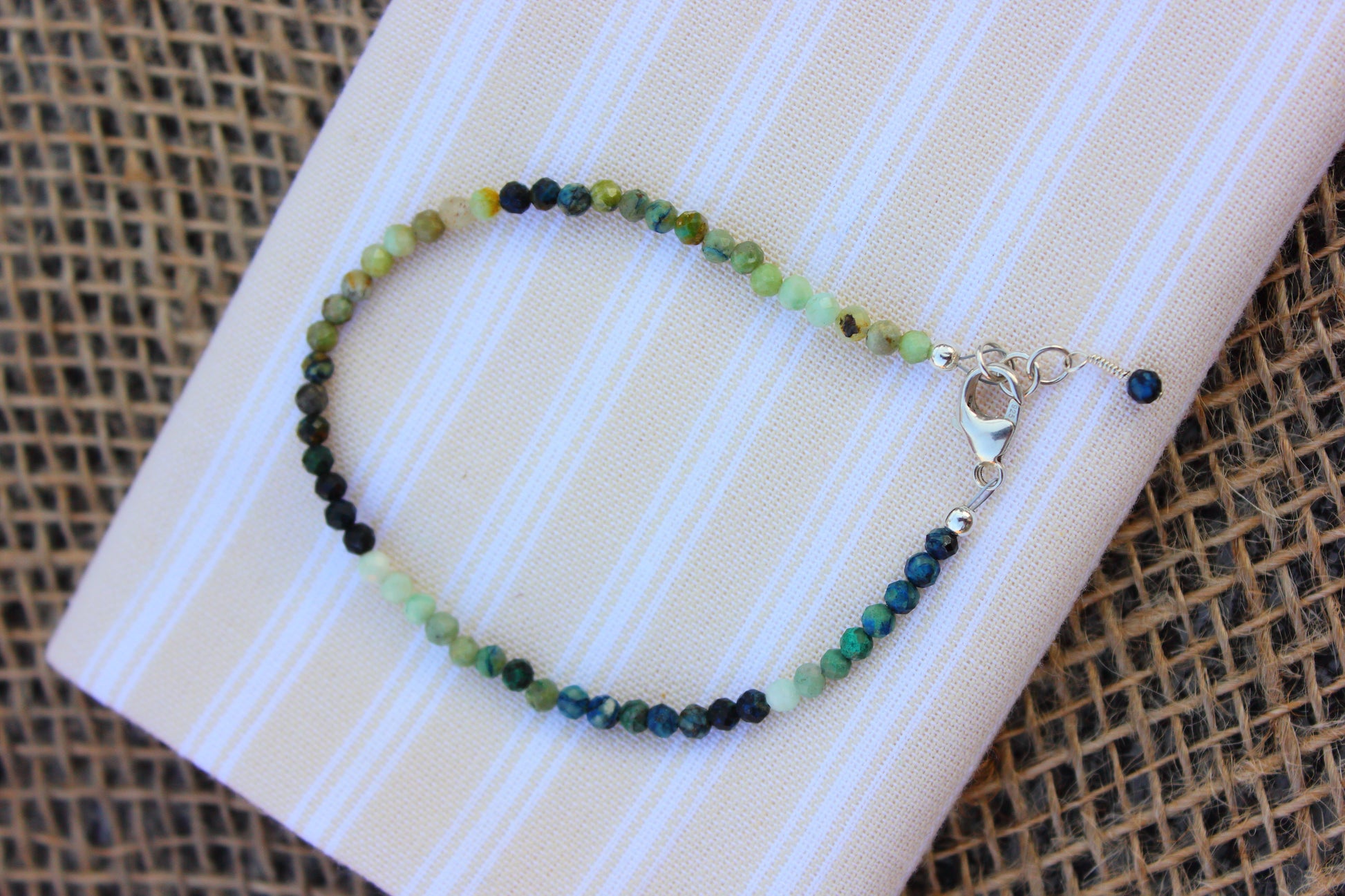 Green beaded bracelet on a white card with a textured brown background