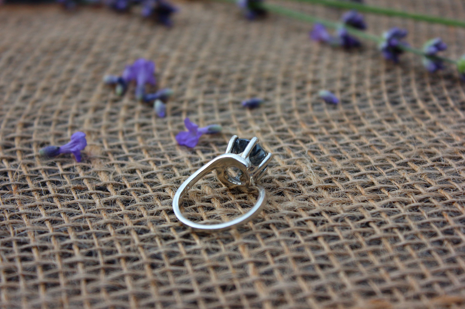 Silver ring on a textured brown surface with scattered purple flowers