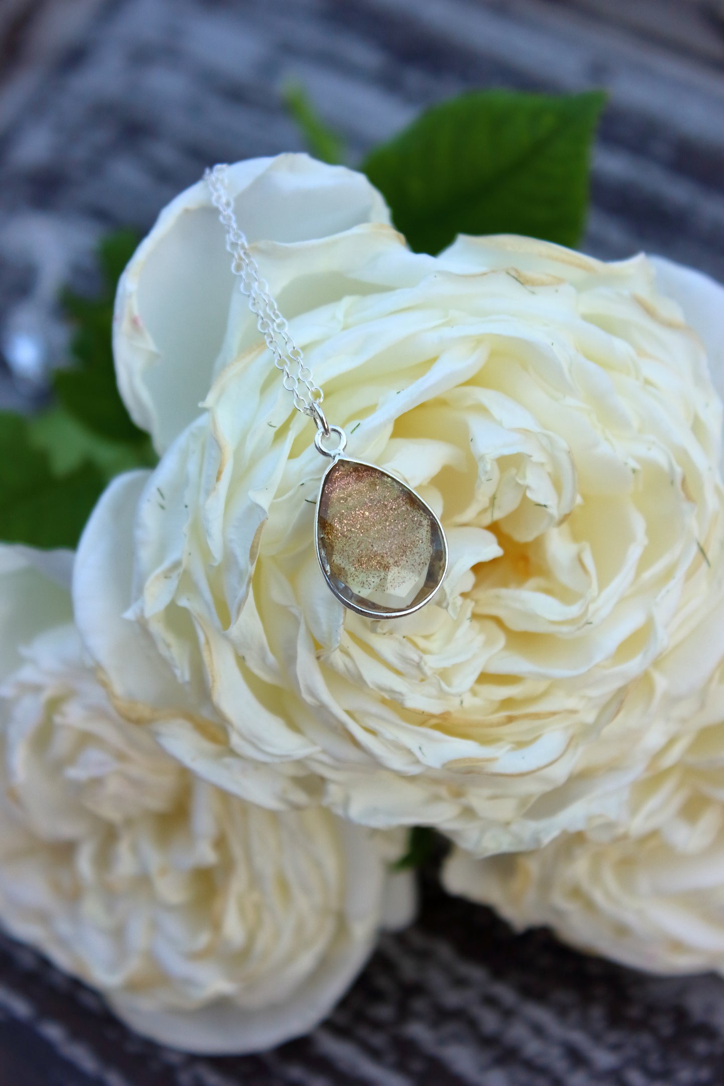 Necklace with a teardrop pendant on a bed of white flowers