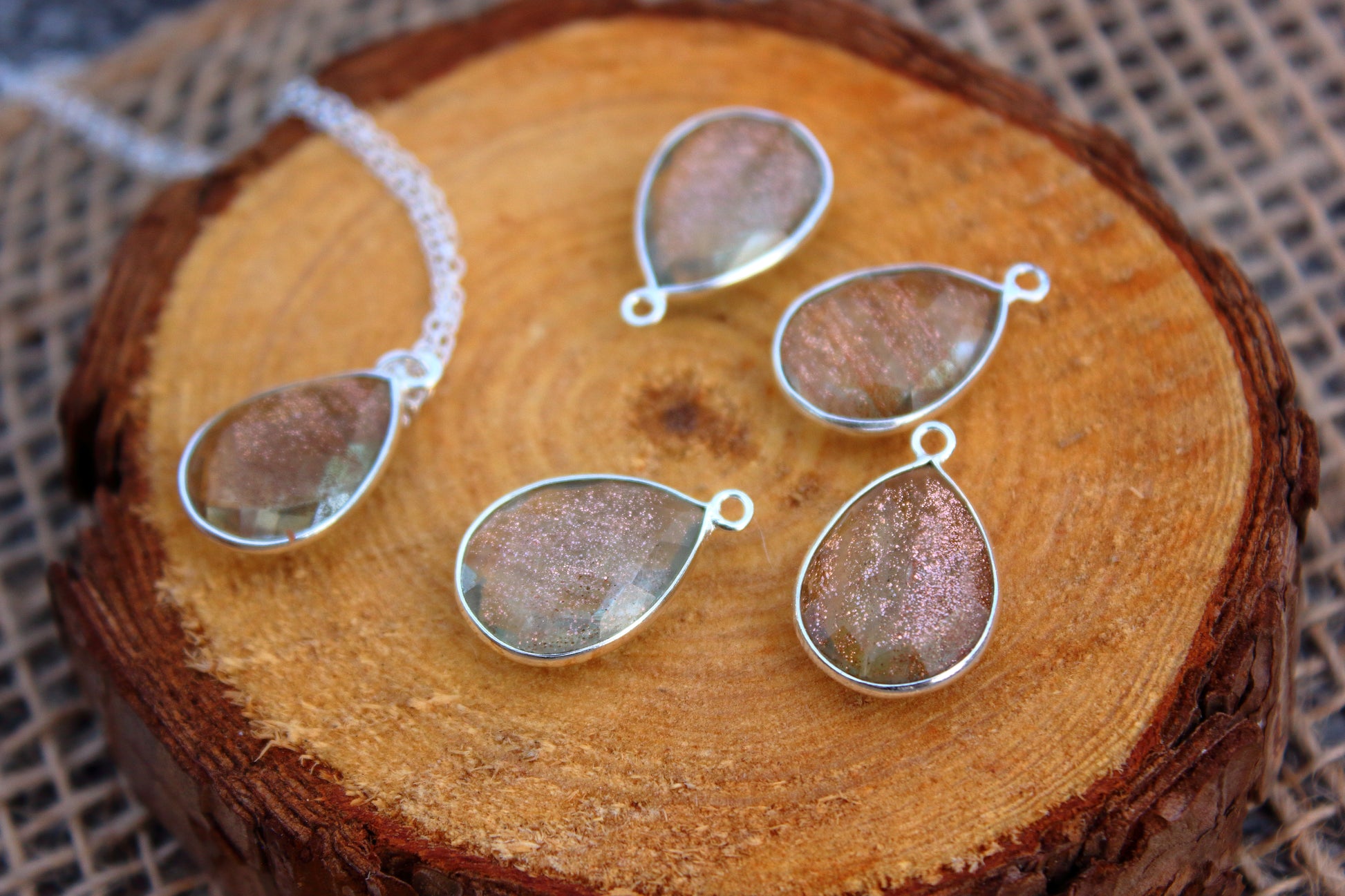Teardrop-shaped silver pendants on a wooden surface