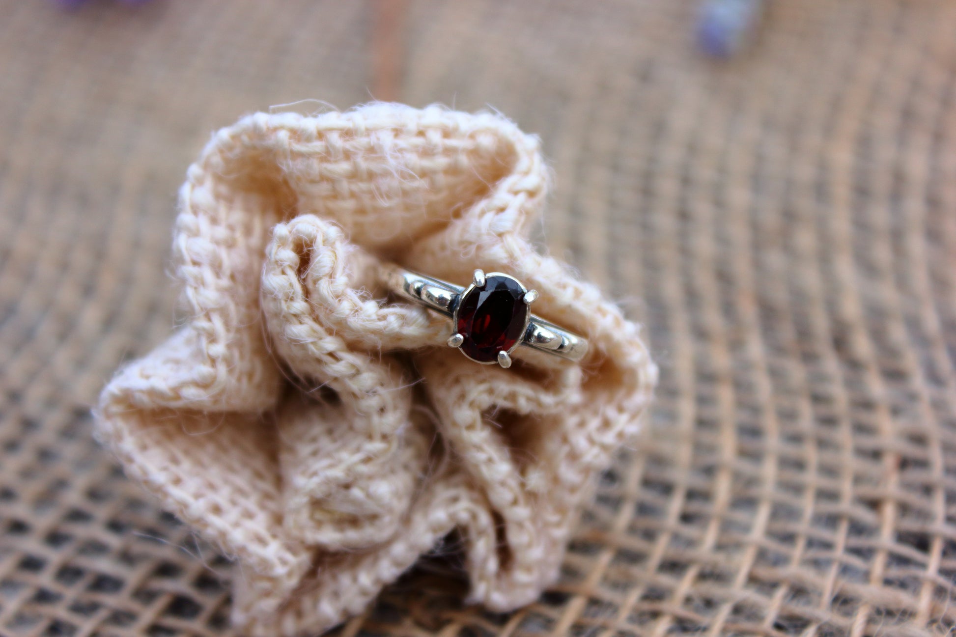 Silver ring with a dark gemstone on a knitted beige flower