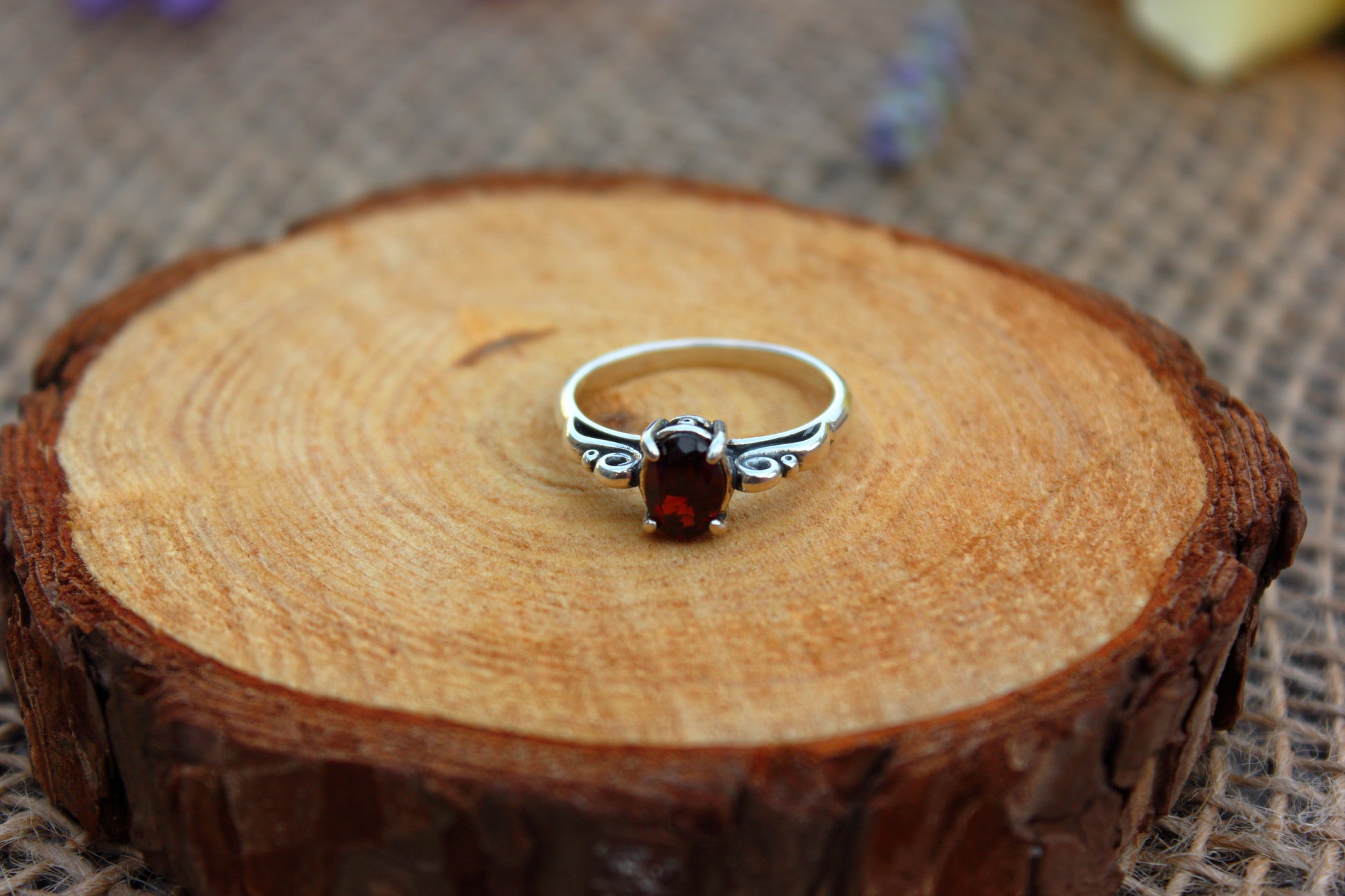 Silver ring with a red gemstone on a wooden surface