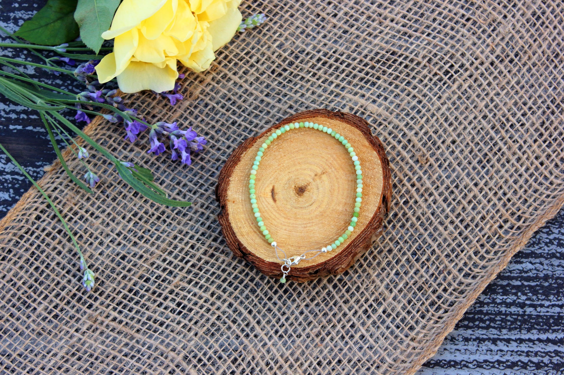 Beaded bracelet on a wooden coaster with flowers and burlap in the background