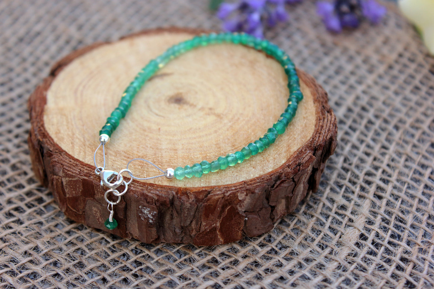 Green beaded necklace on a wooden block with a textured fabric background