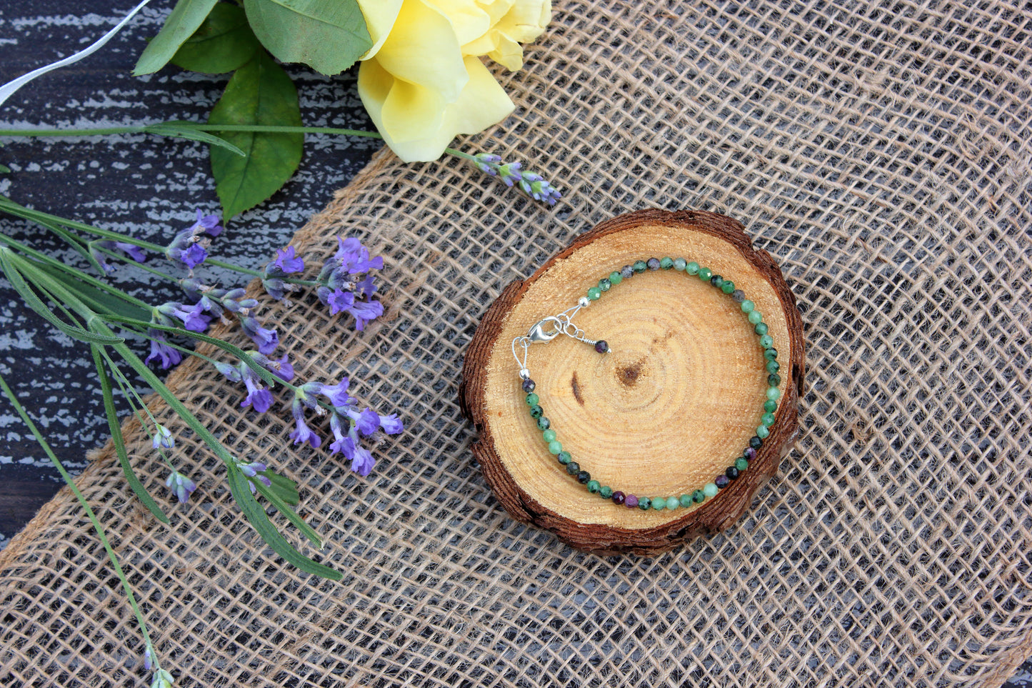 Bracelet on a wooden slice with flowers on a textured surface