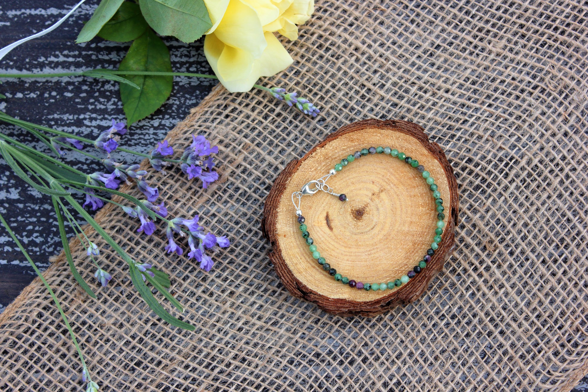 Bracelet on a wooden slice with flowers on a textured surface