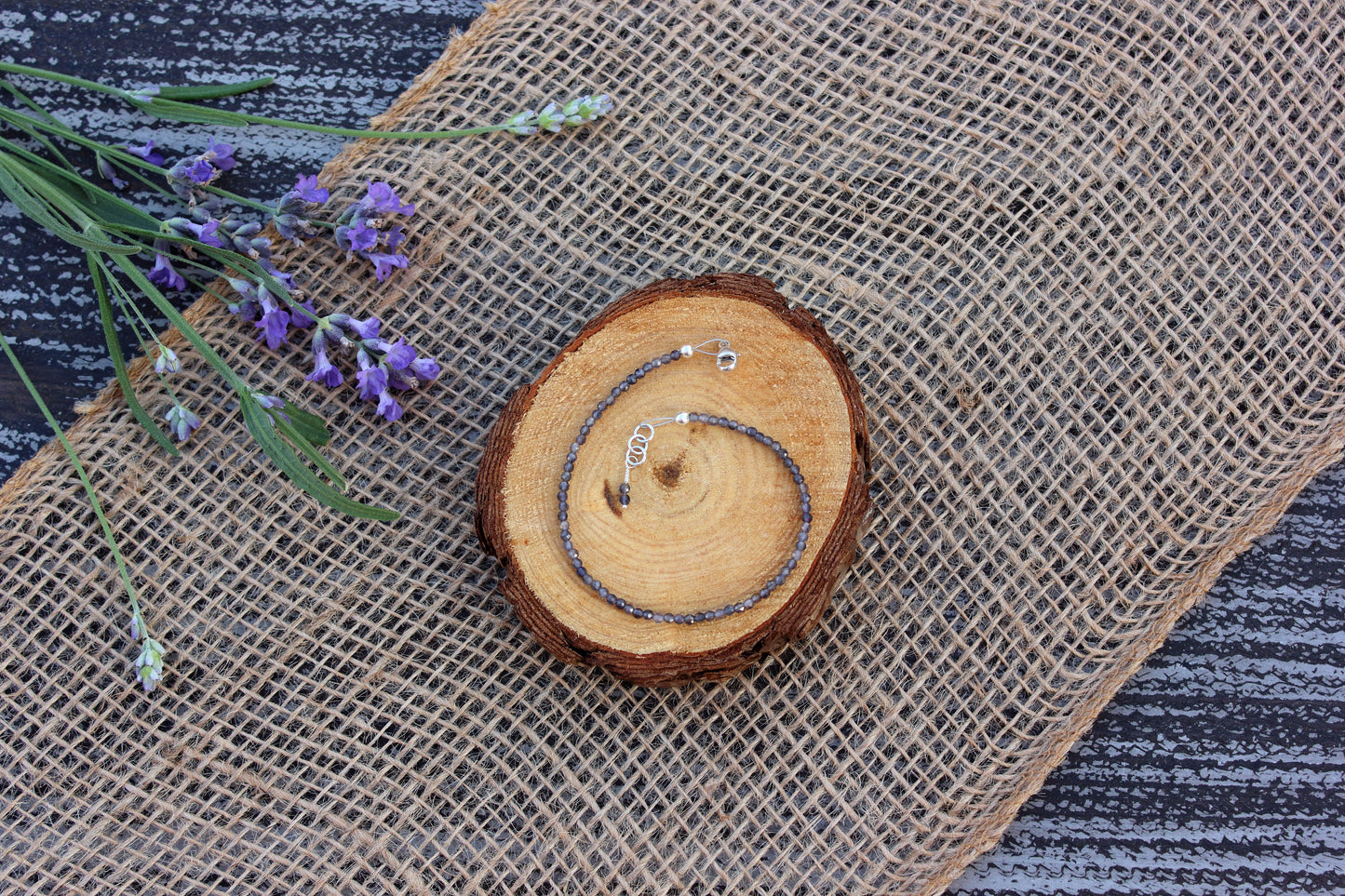 Bracelet with spiral design on a textured fabric background with lavender flowers.