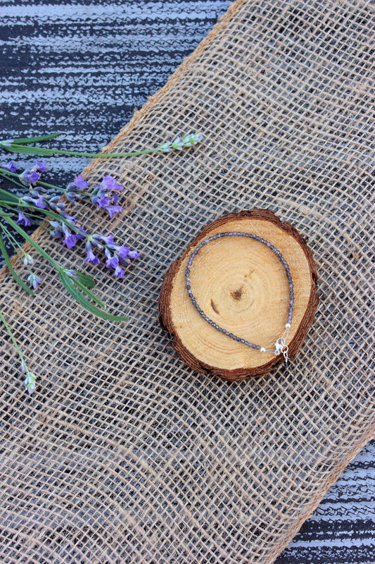 Bracelet on a wooden slice with lavender flowers on a textured fabric background