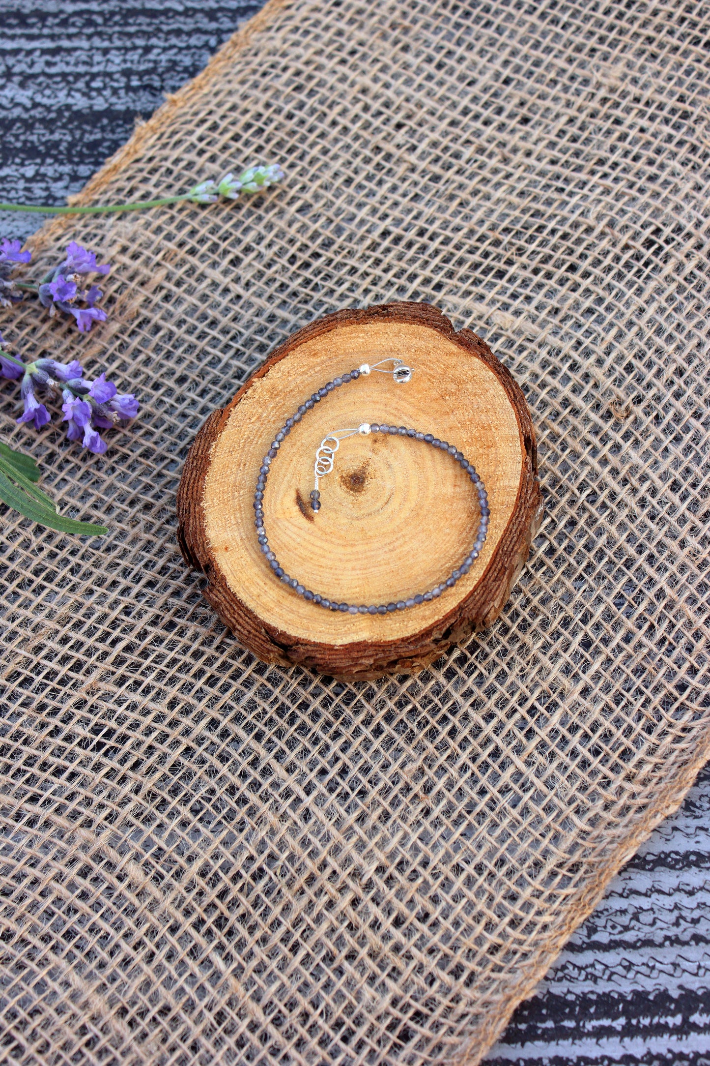 Bracelet on a burlap surface with lavender flowers.