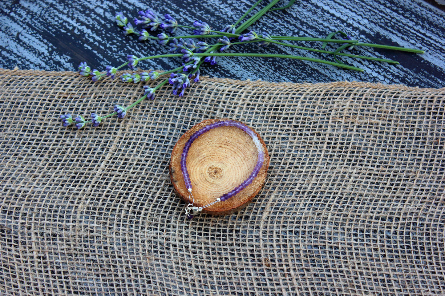 amethyst bracelet with purple accents on a textured surface with lavender flowers.