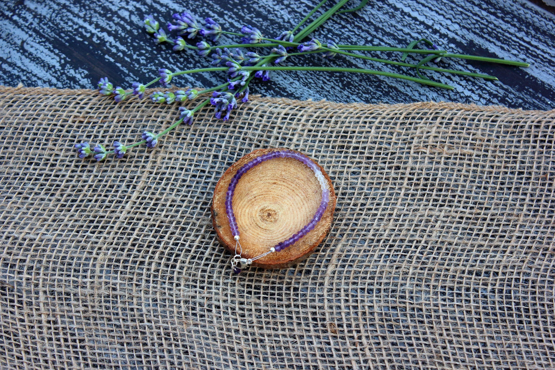 amethyst bracelet with purple accents on a textured surface with lavender flowers.