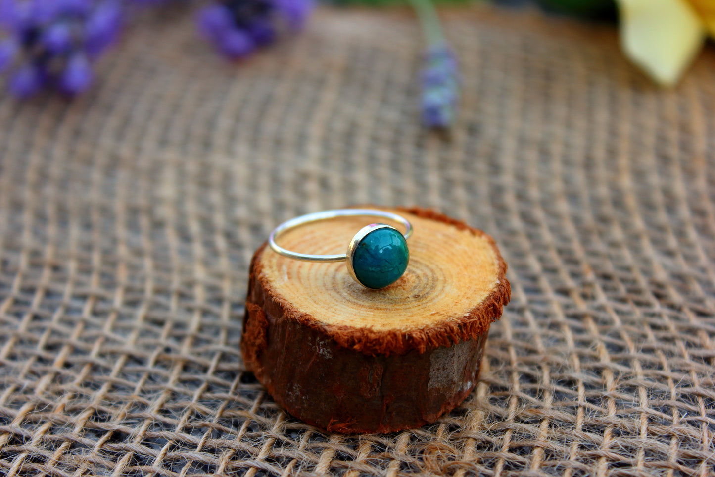 Ring with a chrysocolla stone on a wooden block with a rustic background