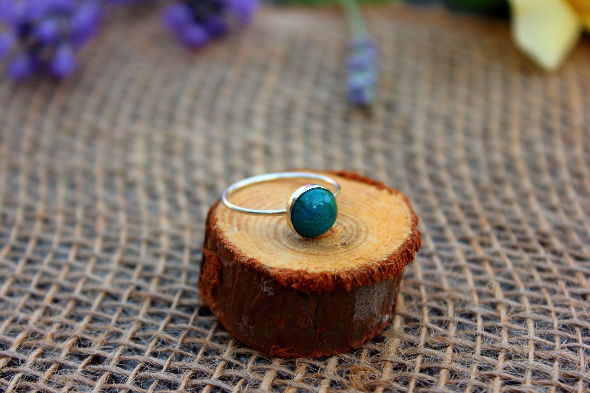 Ring with a chrysocolla stone on a wooden block with a rustic background