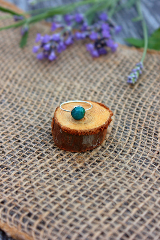 Silver ring with a chrysocolla stone on a wooden stump with lavender flowers in the background