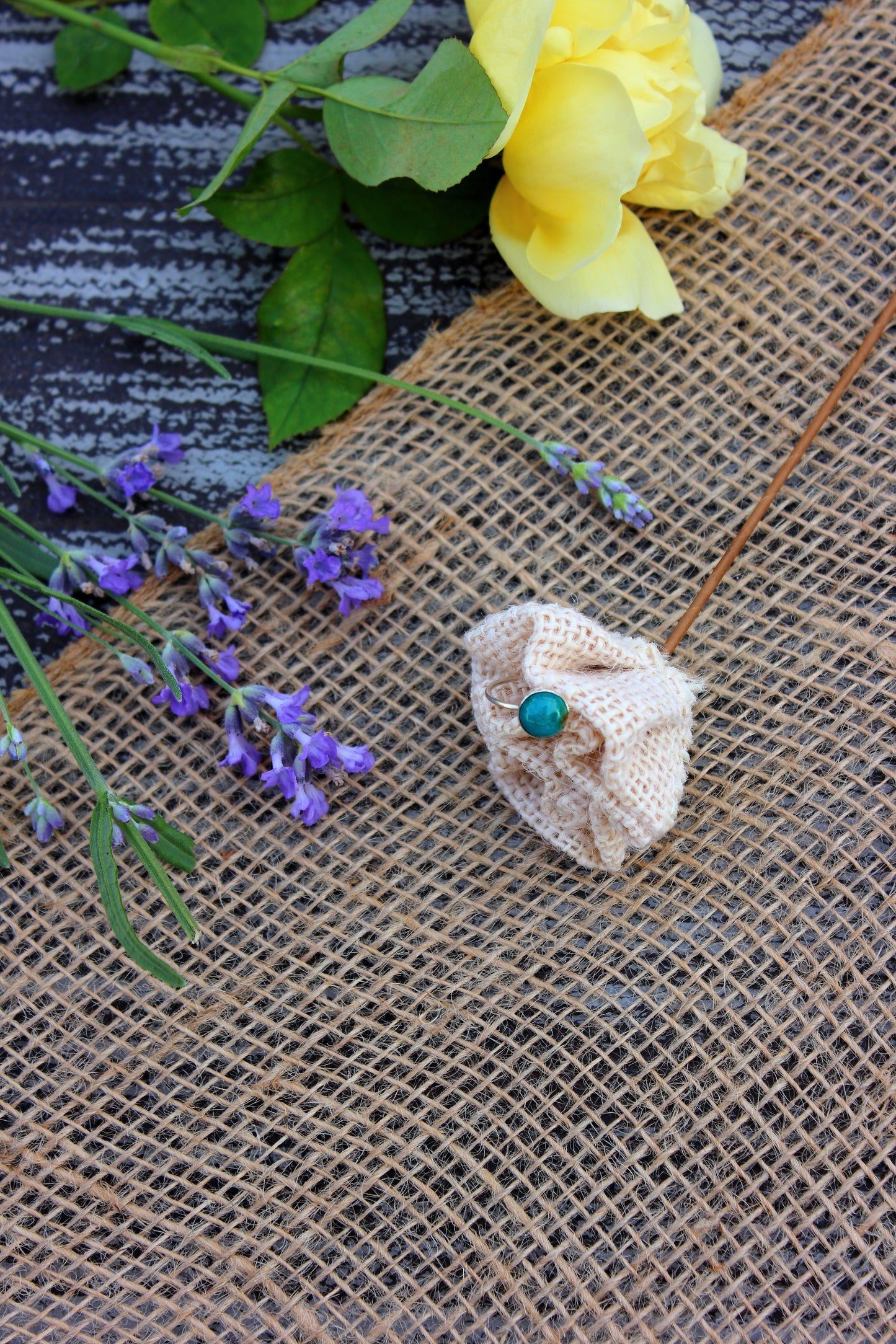 Silver ring with a turquoise stone on a textured surface with flowers